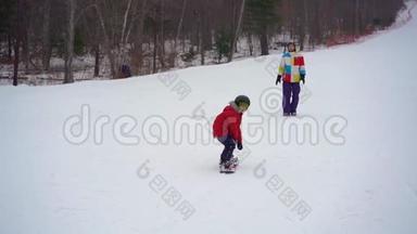 年轻人<strong>滑雪板</strong>教练教小男孩如何骑<strong>滑雪板</strong>。 冬季活动概念。 慢镜头